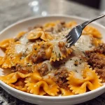 Cajun garlic butter beef served with cheesy bowtie pasta on a plate.