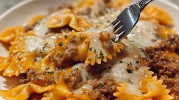 Cajun garlic butter beef served with cheesy bowtie pasta on a plate.