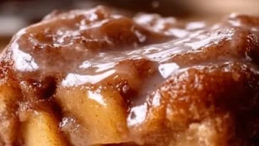 Sweet apple fritter cake topped with glaze and fresh apple slices.